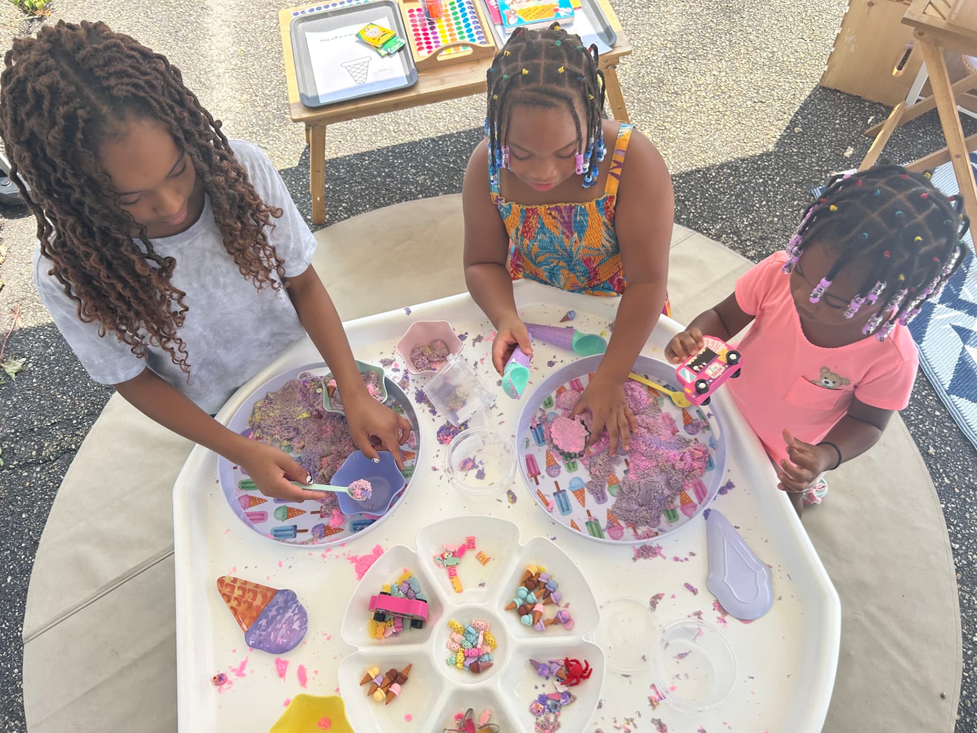 Three children playing with colorful sensory materials around a WonderPlay ice-cream themed activity table