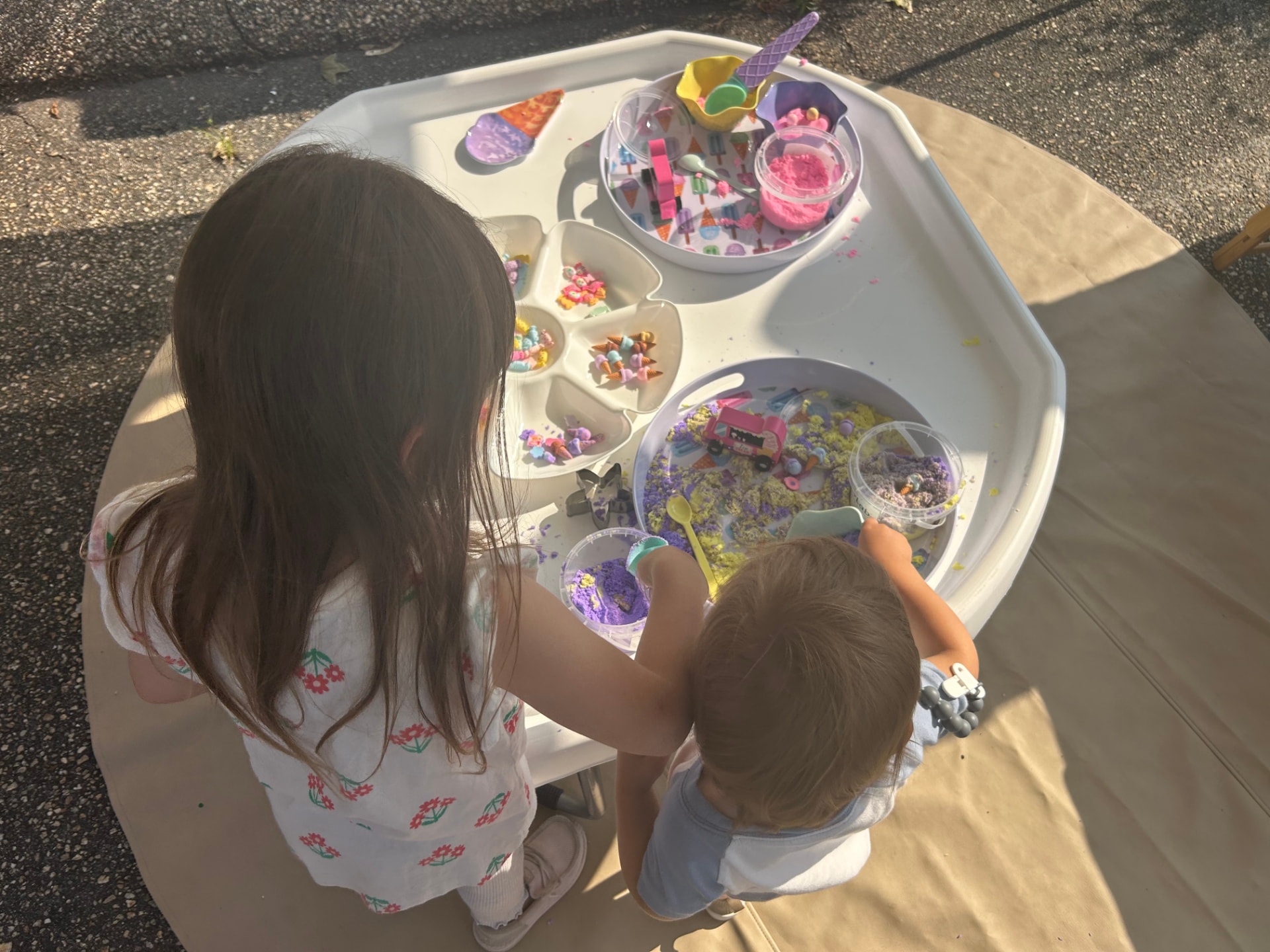 Two children playing together at a white Meka Tuff Tray filled with ice cream themed sensory materials