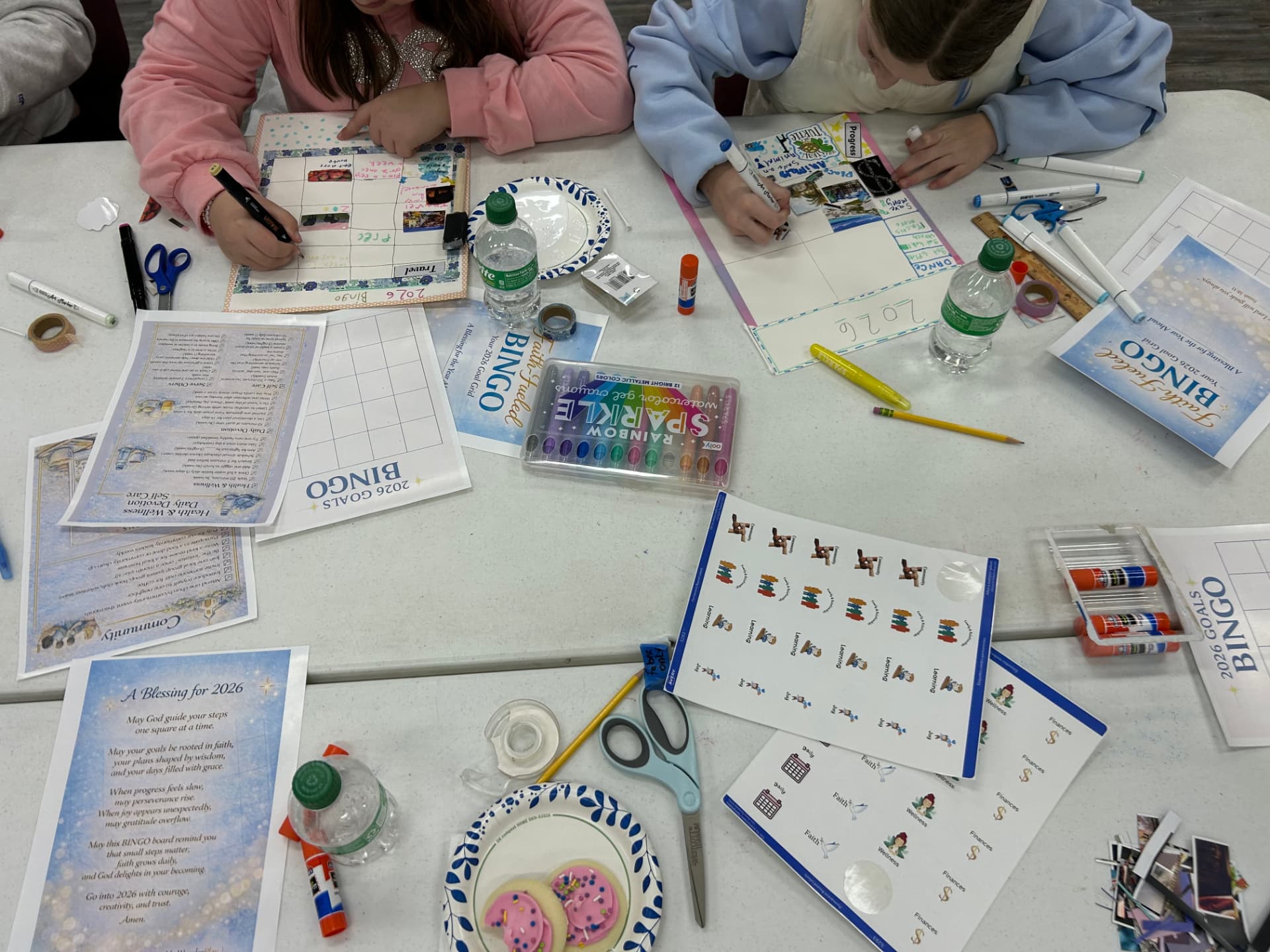 Two children decorating paper bingo boards with markers and stickers at a WonderPlay craft table