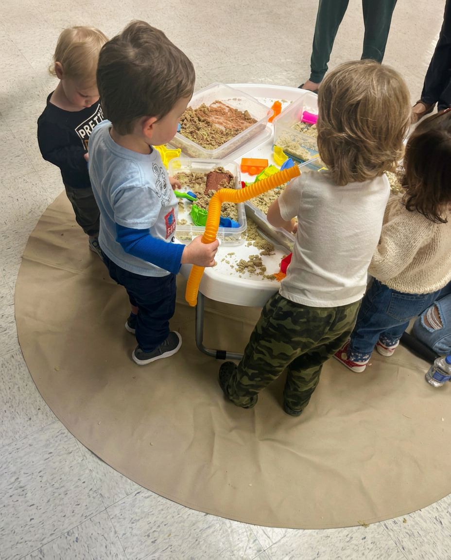 Young children exploring a shared WonderPlay sensory table